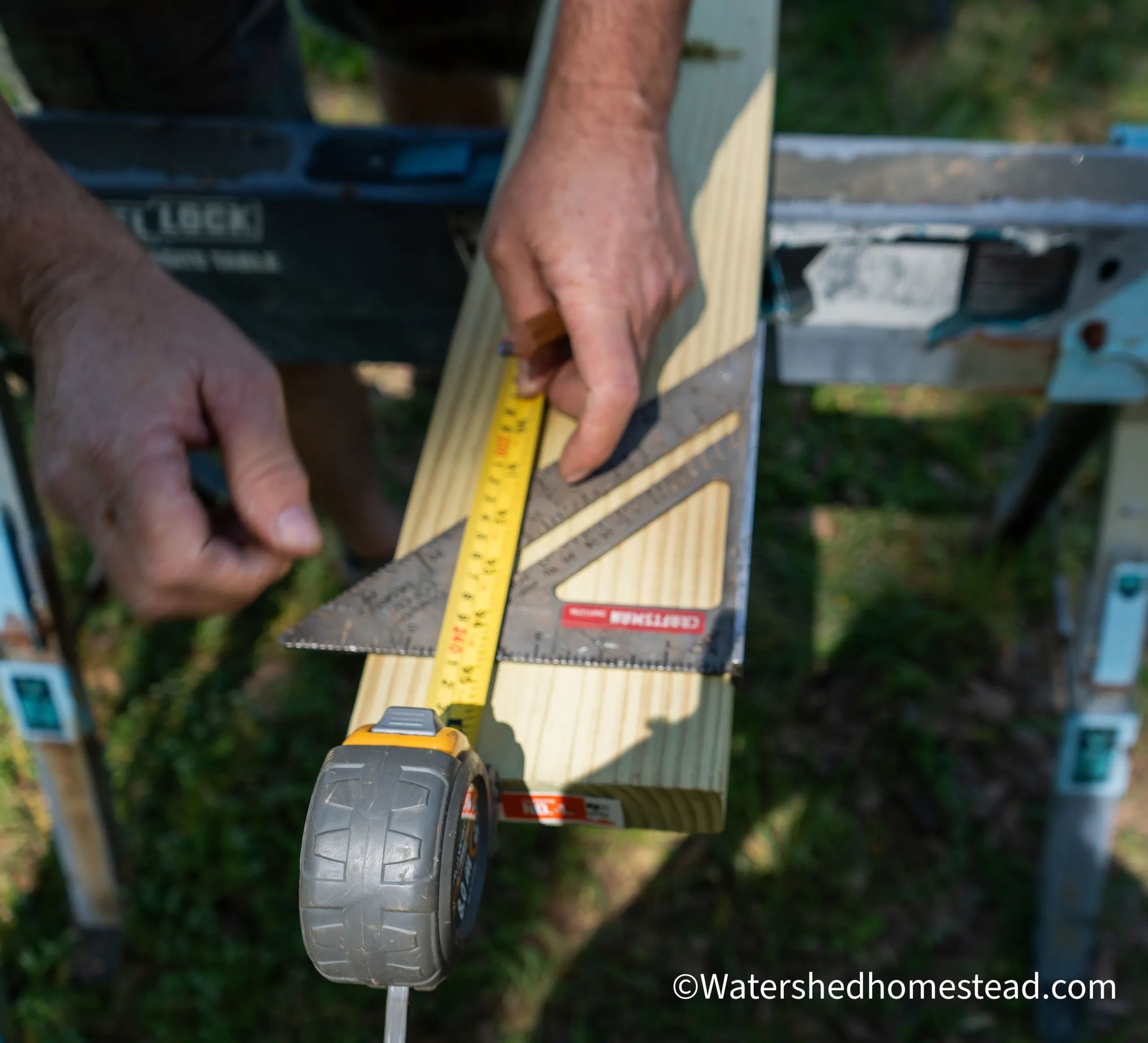 Hands measuring wood with a tape measure and square tool outdoors.