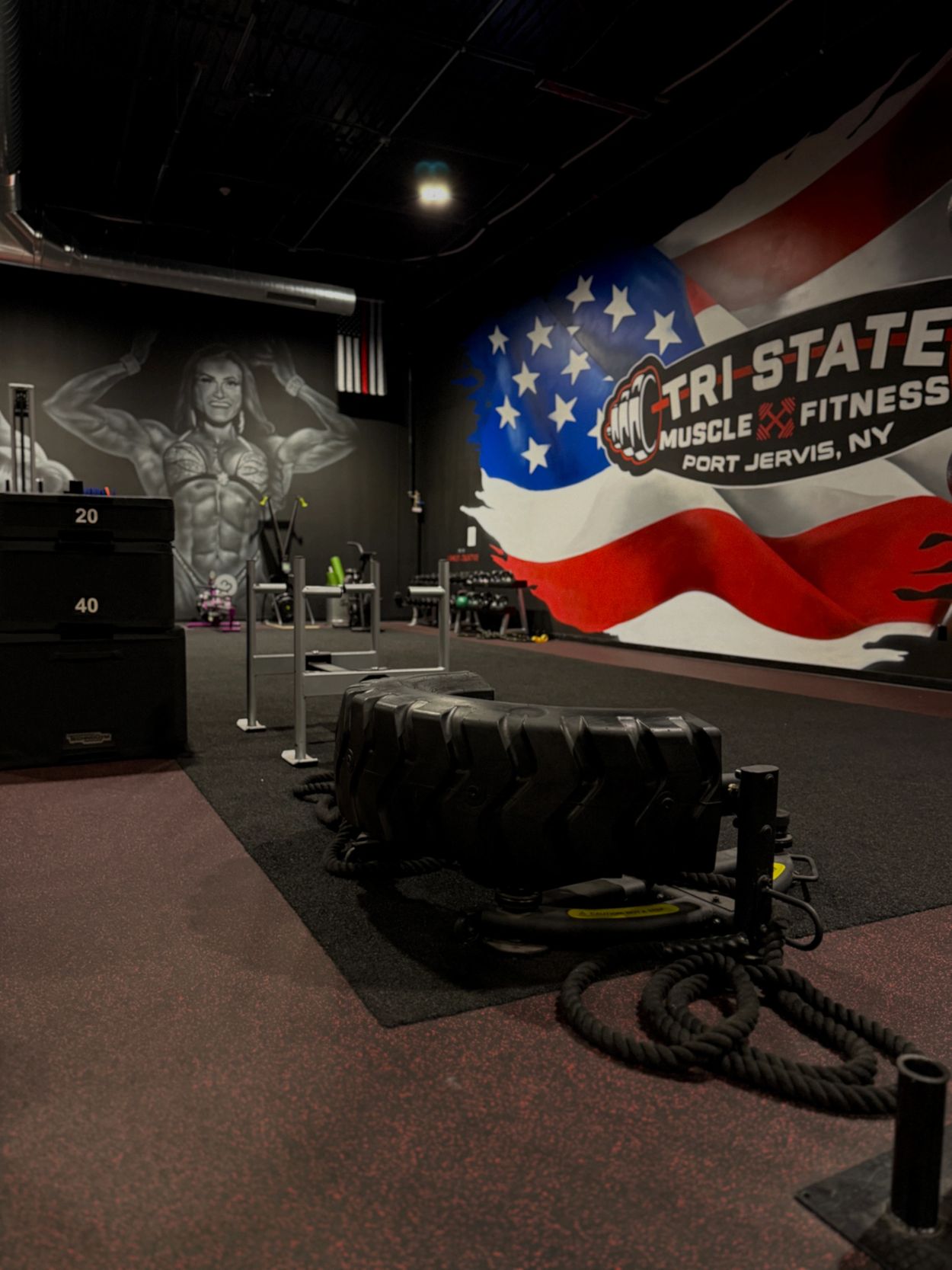 Gym interior with equipment and patriotic mural.