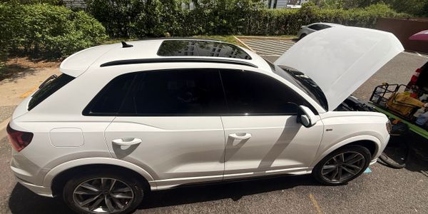 White SUV with open hood parked in a sunny outdoor area.