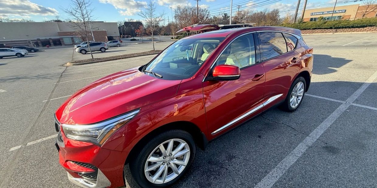 Shiny red SUV parked in a mostly empty parking lot on a sunny day.