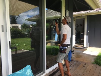 Residential window cleaner on Kauai using professional tools to clean large glass doors and achieve 