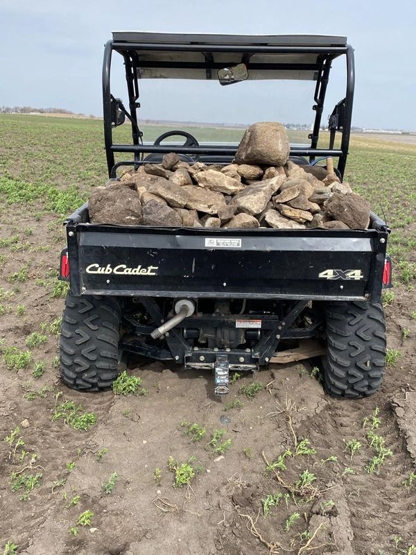 A Cub Cadet 4x4 vehicle loaded with rocks in a field.