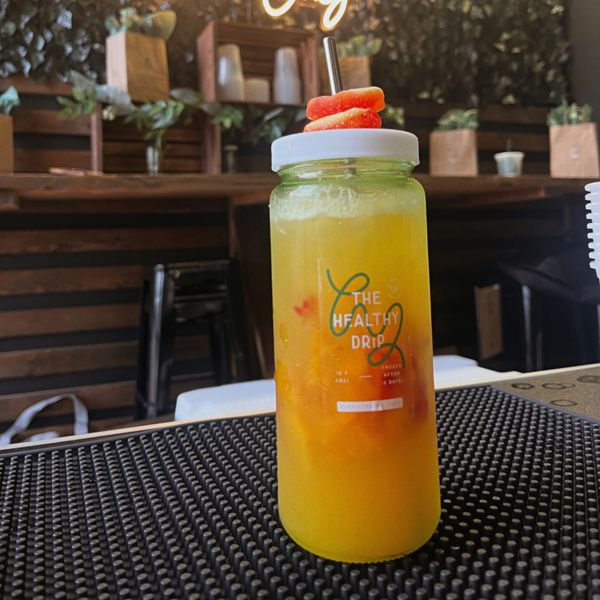 Refreshing yellow drink in a branded bottle with candy garnish on top.