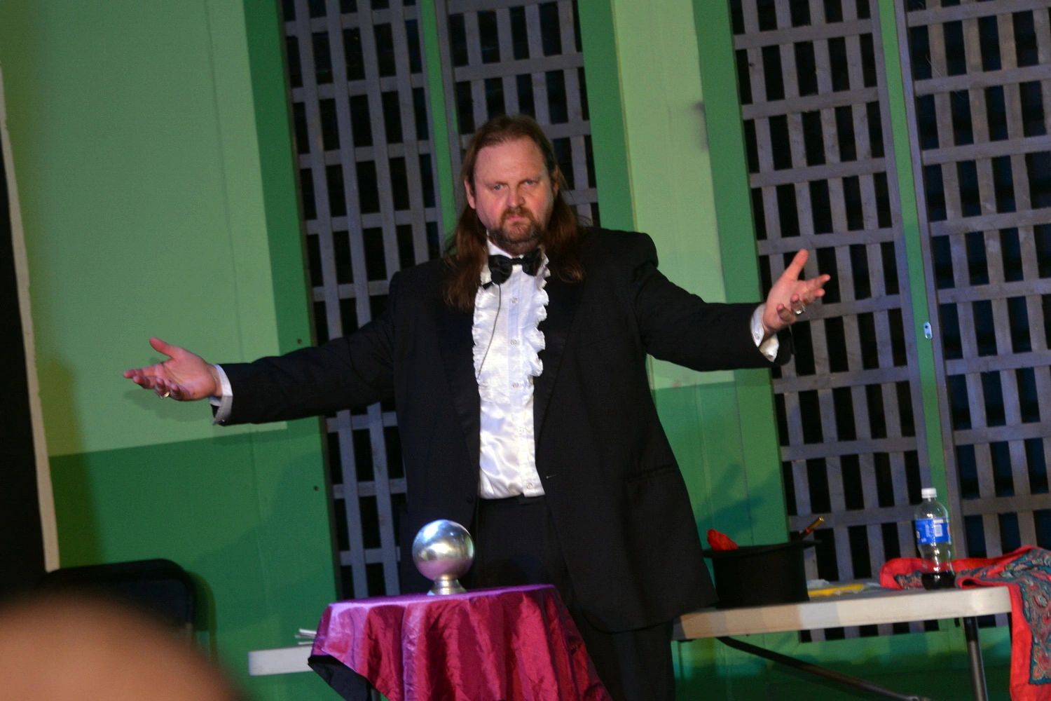 Man in tuxedo performing a magic act with a crystal ball.
