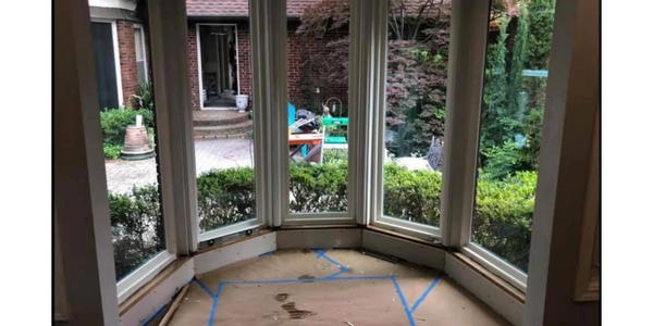 Bay window area under renovation with garden view outside.