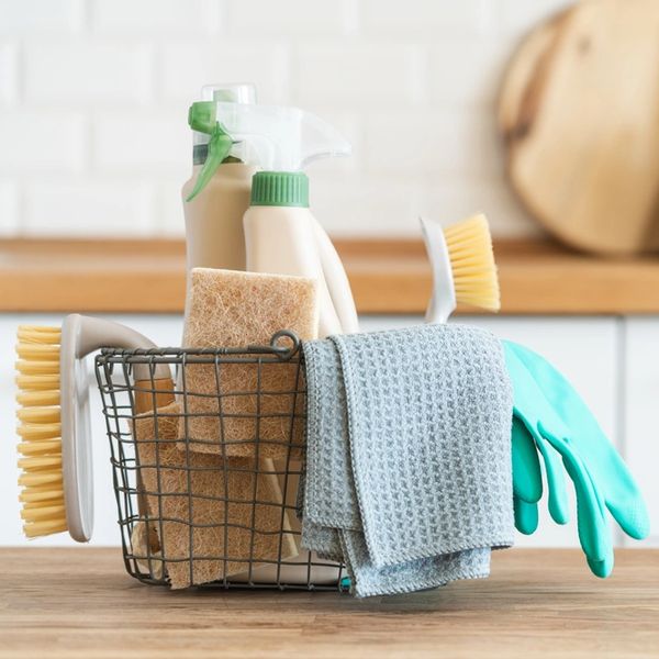 Basket with brushes, rags, natural sponges and cleaning products.