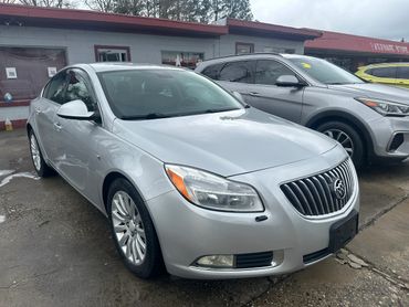 Silver Buick sedan parked outside a dealership on a wet day.