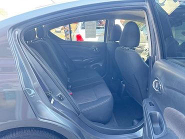 Interior view of a car's back seat with open door and black upholstery.
