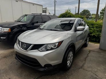 Silver Nissan SUV parked beside a black SUV in a lot.