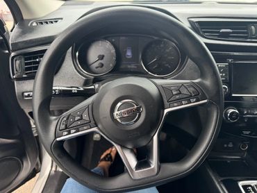 Steering wheel of a Nissan car with dashboard and controls.