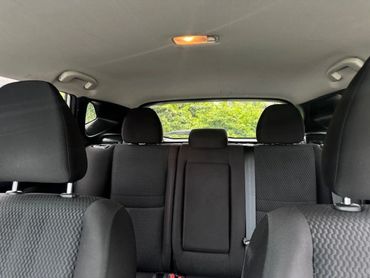 Interior view of a car showing front and back seats with black upholstery.