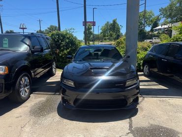 Black sports car parked between two other vehicles in a sunny lot.