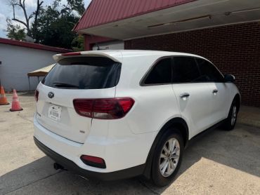 White Kia SUV parked near a building.