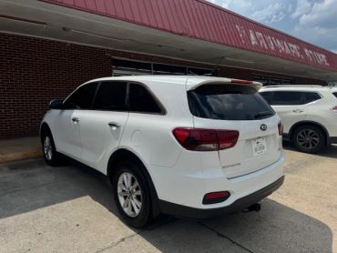 White SUV parked near a brick building under a red awning.