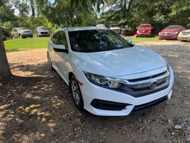 White Honda sedan parked outdoors on gravel.
