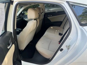 Interior view of a car's back seat with beige upholstery.