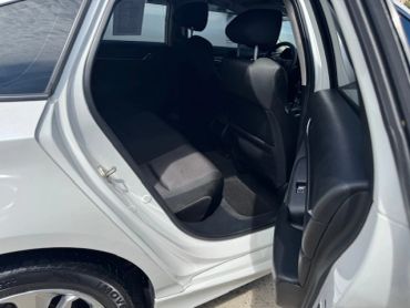 Open car door showing back passenger seat in a white vehicle.
