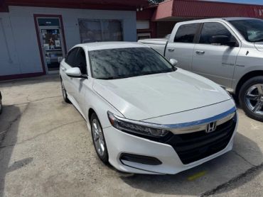 White Honda sedan parked outdoors next to a gray truck.