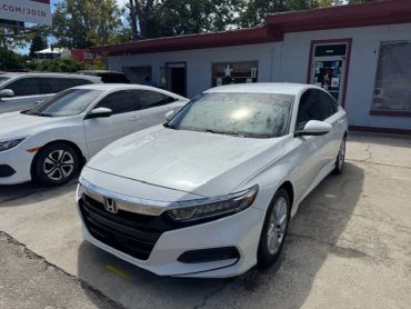 White Honda sedan parked outside a building.