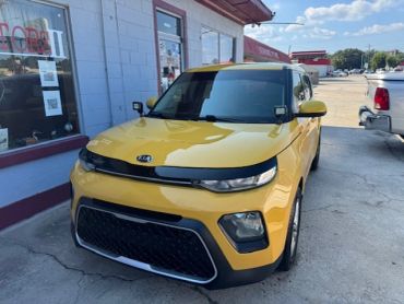 Yellow Kia Soul parked outside a store.