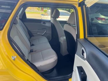 Rear seats of a yellow car with beige upholstery.