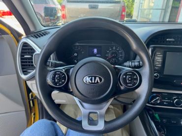Steering wheel of a Kia car with dashboard in the background.