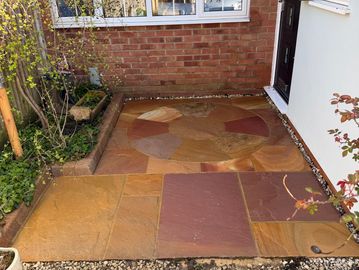 Newly laid multicolored stone patio outside a house door.