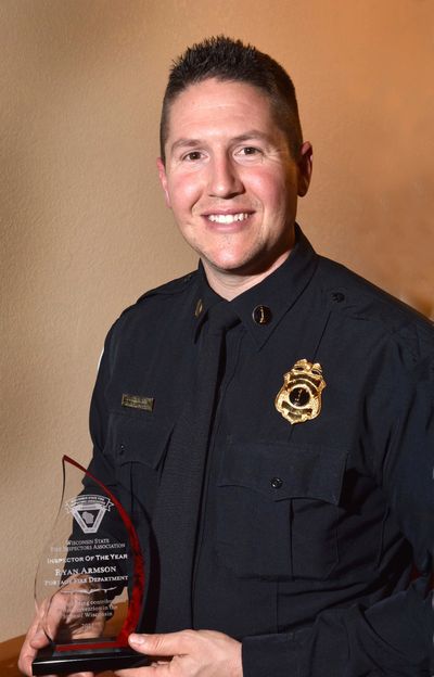 Firefighter holding an award trophy, smiling.