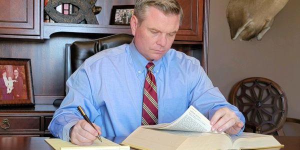 Man in office reading and taking notes with focus.
