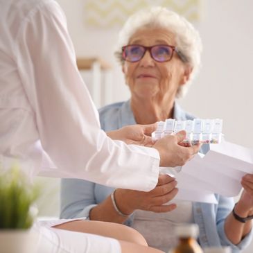 A carer helping an elderly woman to take her medication