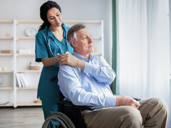 A nurse taking care of an older man in a wheel chair