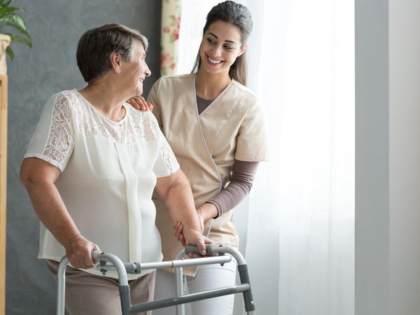 A carer helping an elderly woman to walk