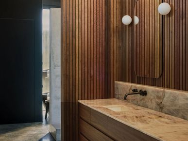 Modern bathroom with wood paneling and marble countertop.