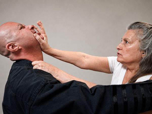 Woman pushing man's face away forcefully.