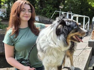 A woman with glasses holding a fluffy dog.