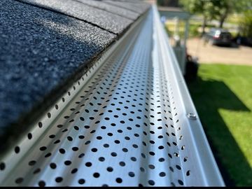 Close-up of a perforated rain gutter guard on a roof.