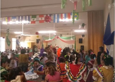 photo of a party in the hall decorated with flags with ladies in Mexican costumes.