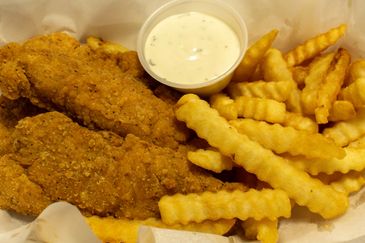 Crispy chicken tenders with crinkle-cut fries and a cup of dipping sauce.