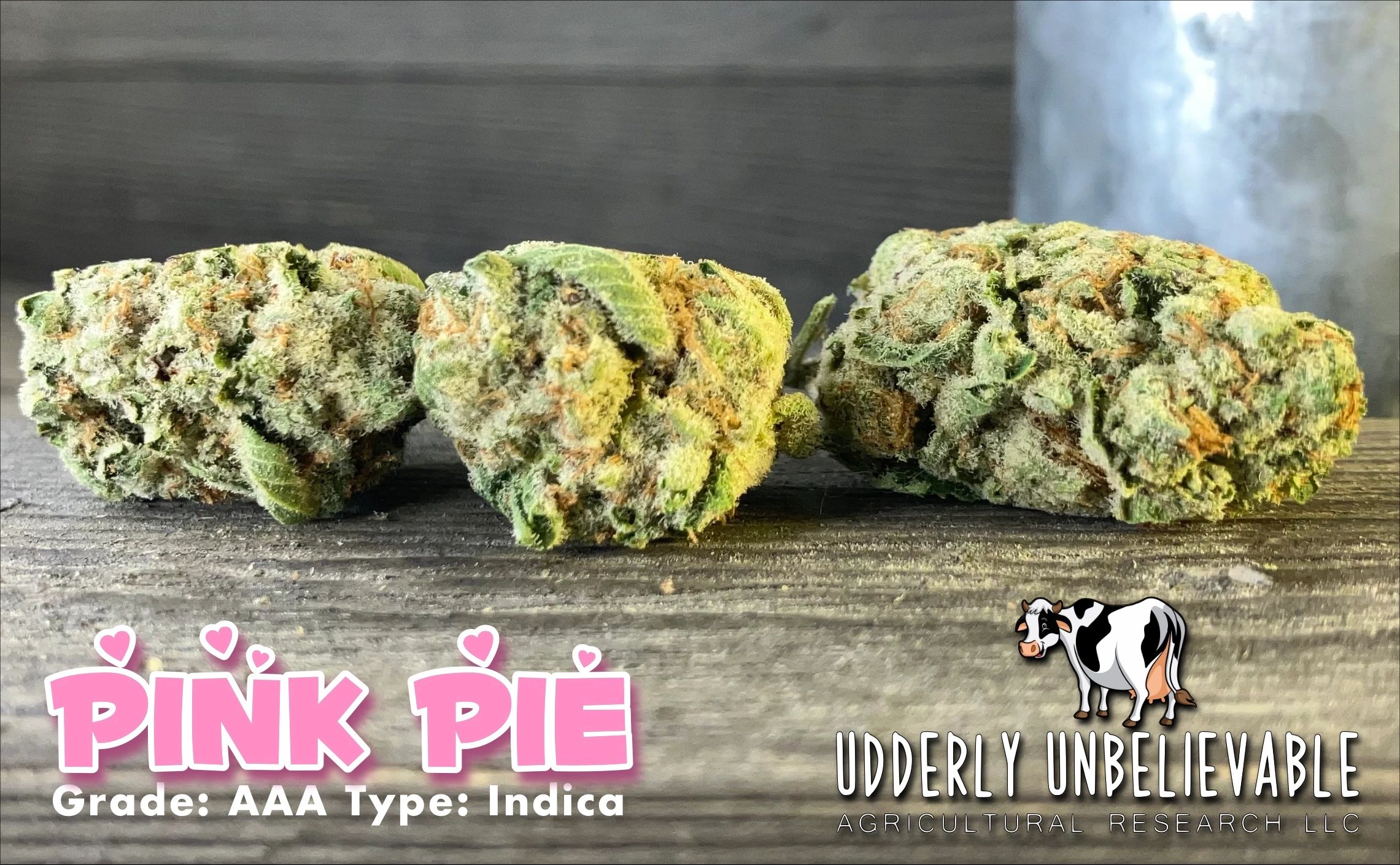 Close-up of Pink Pie indica cannabis buds with company branding.