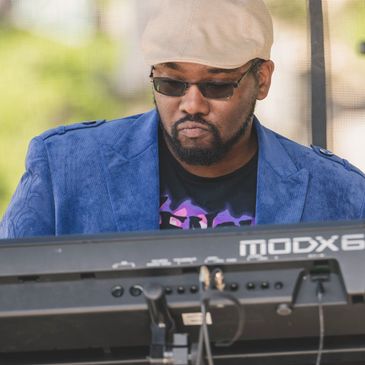 Man playing keyboard outdoors in blue jacket.