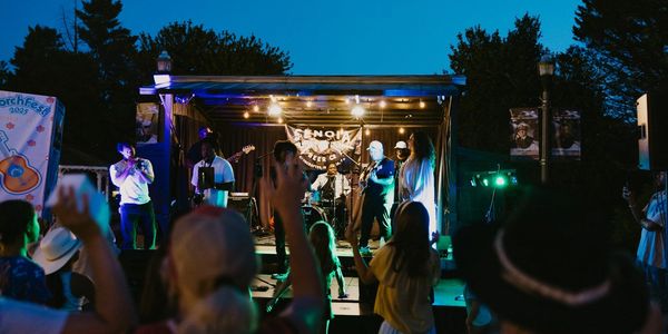 Outdoor nighttime concert with a lively crowd and band on stage.