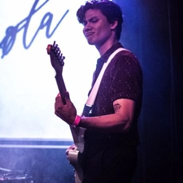 Young man playing electric guitar on stage.