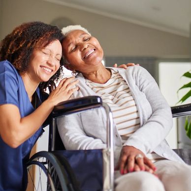 Caregiver and elderly woman sharing a joyful moment at home.