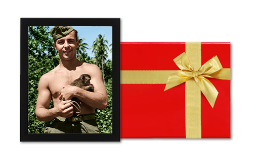 Young soldier holding a puppy next to a red gift box with a golden bow.