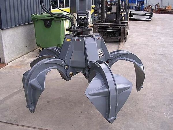 Industrial hydraulic grapple attachment with four large claws for heavy lifting.