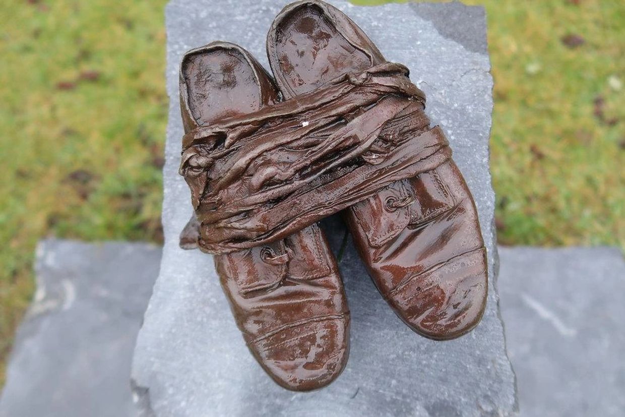 Close-up of worn brown leather shoes with laces tied together.