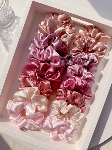 Pink and purple satin scrunchies in a white tray.