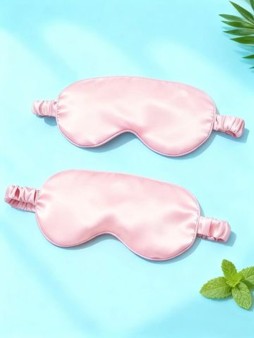 Two pink silk sleep masks on a blue background.