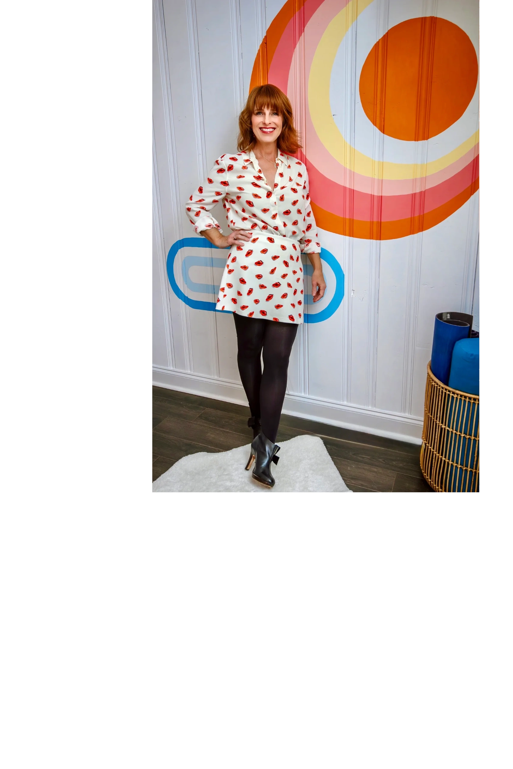 Woman in a lip-print dress posing against a colorful wall mural.