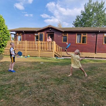 Guests are playing outside the 4-bedroom hot tub lodge. Book Pack Relax, Lakeside 28 in Carnforth.